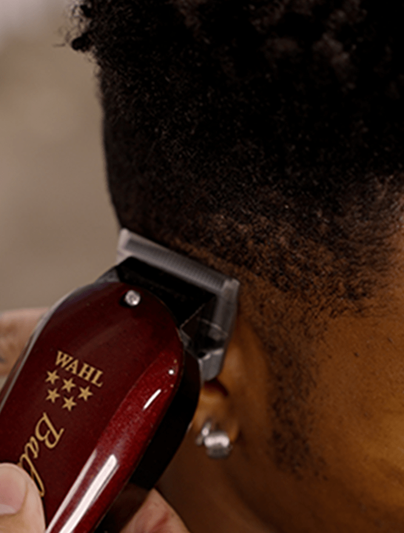 Barber using Wahl Balding Clipper to cut a fade into model's hair